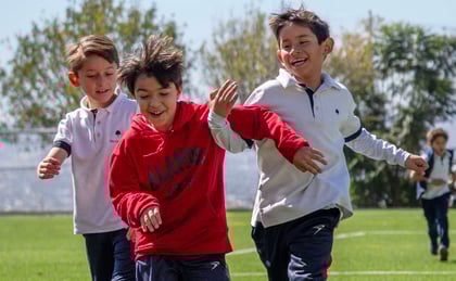 Niños de Primaria (ES) corriendo felices en la cancha del Colegio Álamos Querétaro