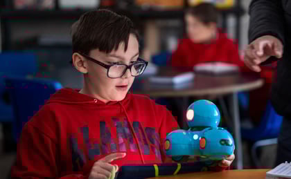 Alumno de Secundaria (JH) del Colegio Álamos interactuando con una tableta y un pequeño robot
