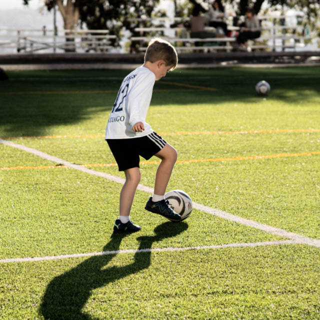 Niño llevando un balon de futbol por la cancha del Álamos