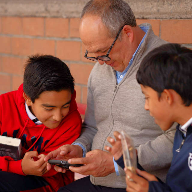 Profesor y alumnos de primaria del Colegio Álamos observan una tableta